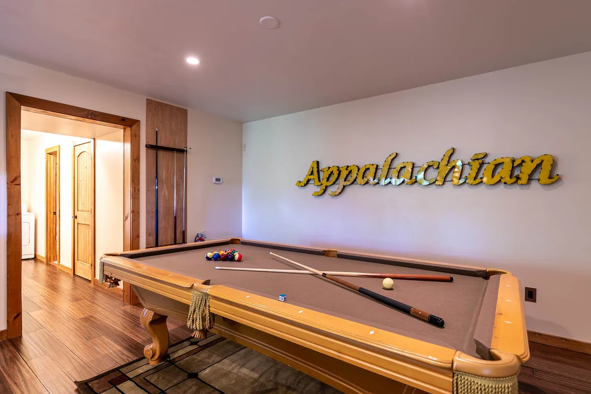 A stylish interior game room featuring a pool table and decorative wall sign, designed for lively social gatherings and friendly competition among friends.